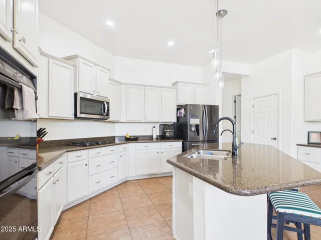 a kitchen with granite countertop a sink a counter top space appliances and cabinets