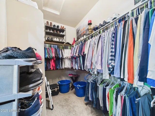a view of walk in closet with clothes and shoes