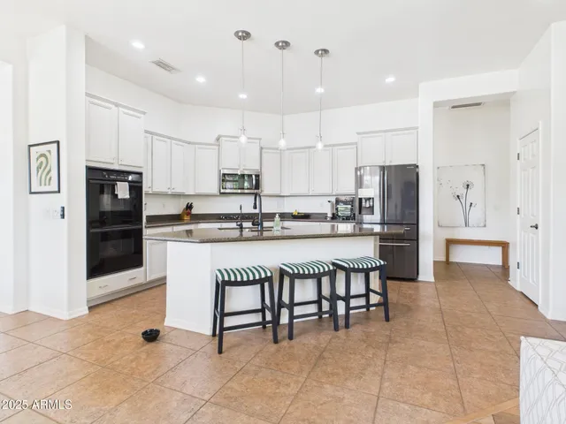 a kitchen with stainless steel appliances kitchen island granite countertop a refrigerator and a stove top oven