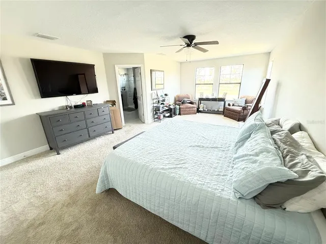 a spacious bedroom with a bed and a flat screen tv