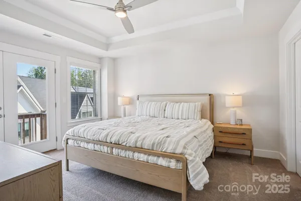a bedroom with a bed next to a window with a chandelier