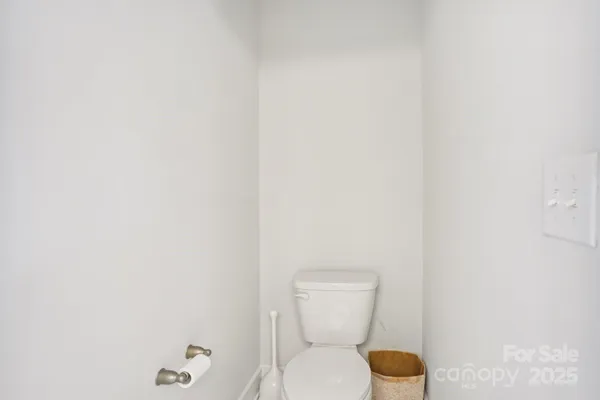 a white toilet sitting next to a white wall