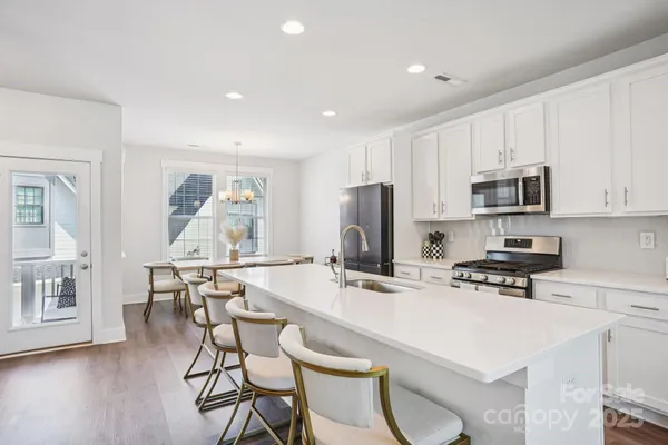 a kitchen with stainless steel appliances a microwave a stove a refrigerator a table and chairs