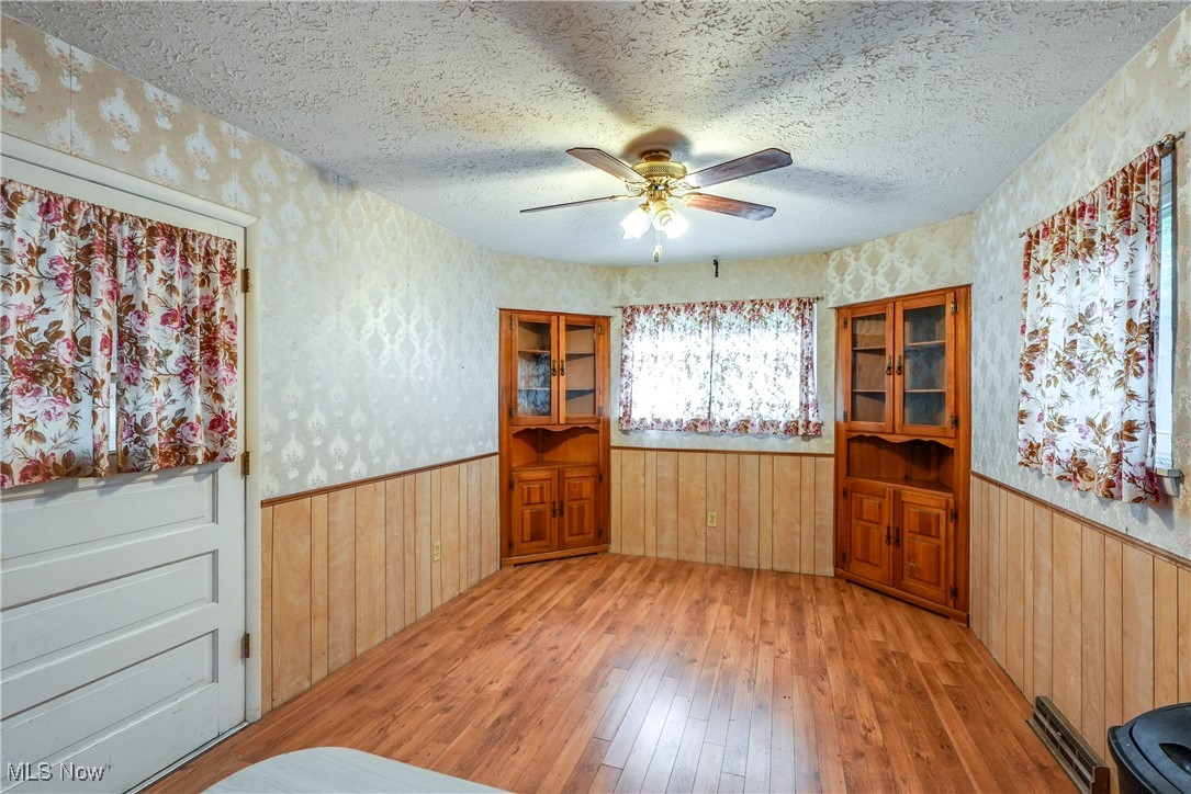 2123 Martin Road Mogadore, OH 44260 - Photo 14 of 35 Spare room with hardwood / wood-style flooring, wallpapered walls, wainscoting, a textured ceiling, and ceiling fan