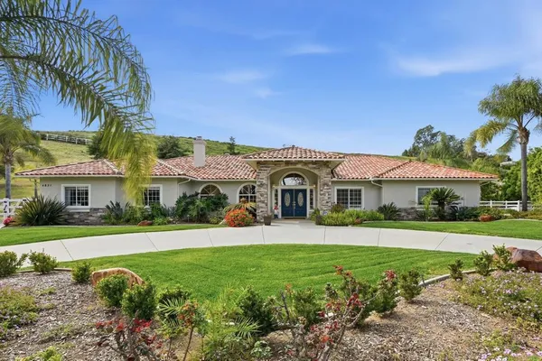a front view of a house with a yard and potted plants