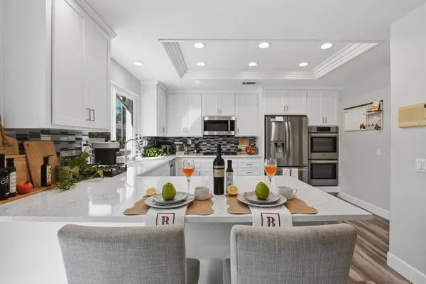 a kitchen with granite countertop white cabinets and stainless steel appliances