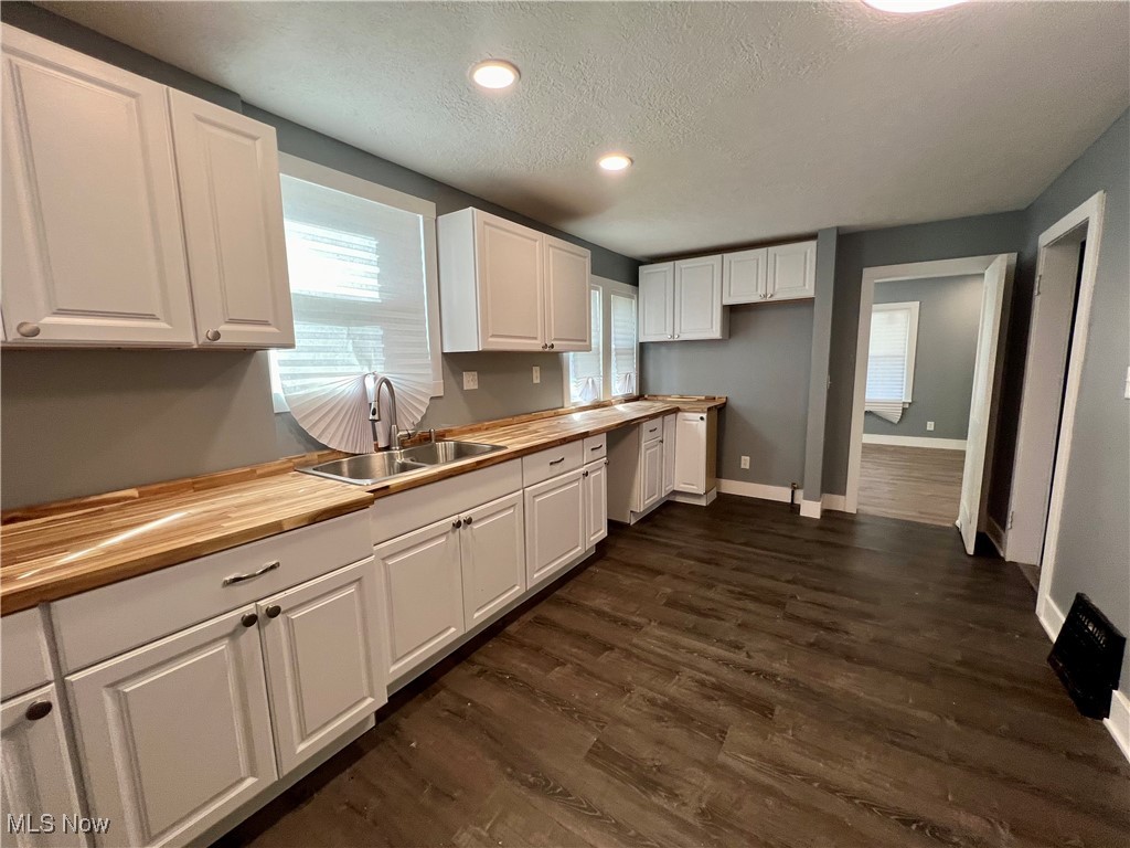 1024 Copley Road Akron, OH 44320 - Photo 9 of 31 Kitchen featuring wooden counters, dark wood-type flooring, sink, white cabinetry, and a textured ceiling