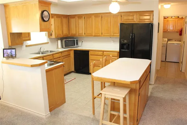 a kitchen with a refrigerator a stove a sink dishwasher and wooden cabinets with a dining table