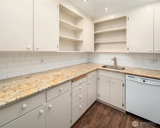 a kitchen with granite countertop white cabinets and a sink