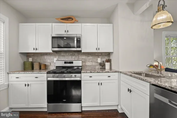 a living room with stainless steel appliances furniture and a kitchen view
