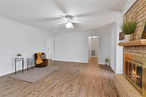 a view of an empty room with wooden floor and a fireplace