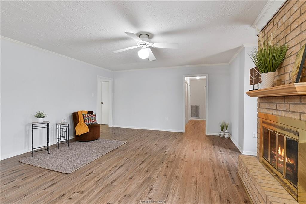 1031 Rose Circle College Station, TX 77840 - Photo 13 of 26 Sitting room with ornamental molding, light wood-style floors, a fireplace, a textured ceiling, and a ceiling fan