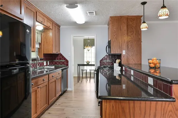 a kitchen with stainless steel appliances granite countertop a refrigerator a stove and a sink with wooden floor