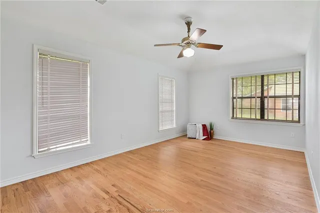 an empty room with wooden floor cabinet and windows