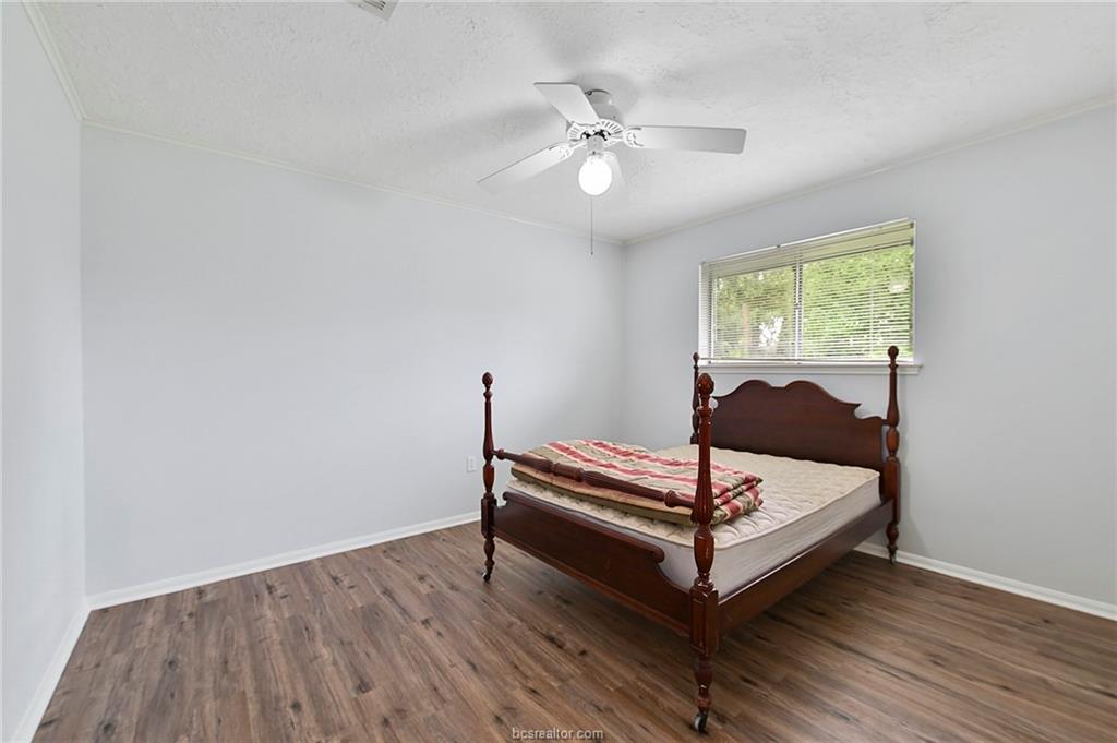 1031 Rose Circle College Station, TX 77840 - Photo 21 of 26 Bedroom with dark wood finished floors, ceiling fan, crown molding, and a textured ceiling
