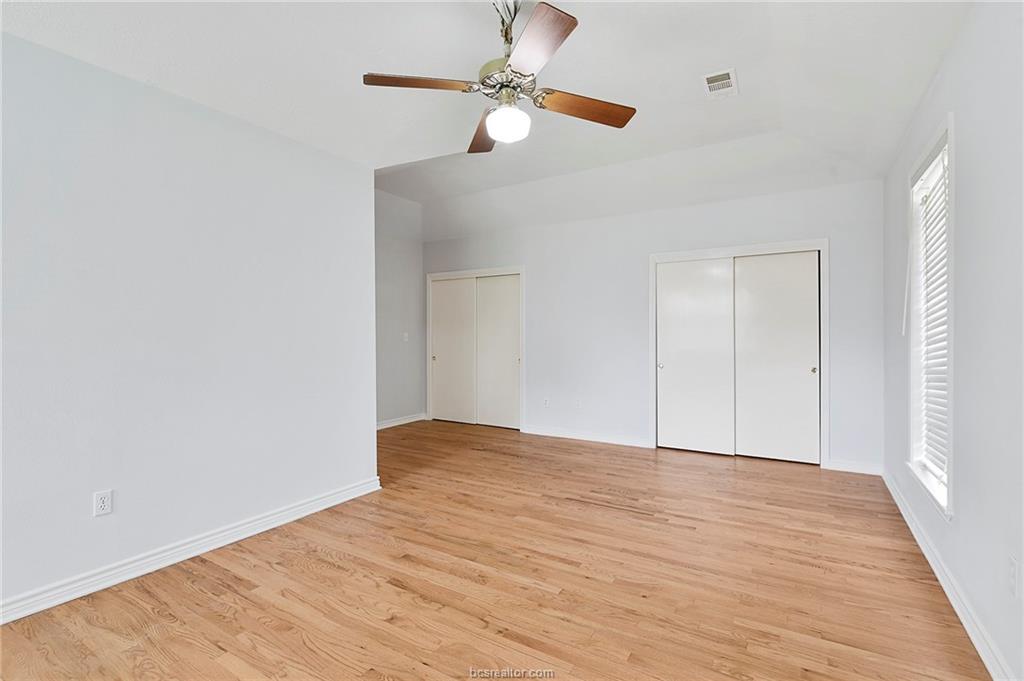 1031 Rose Circle College Station, TX 77840 - Photo 3 of 26 Unfurnished bedroom with two closets, light wood-style floors, and a ceiling fan