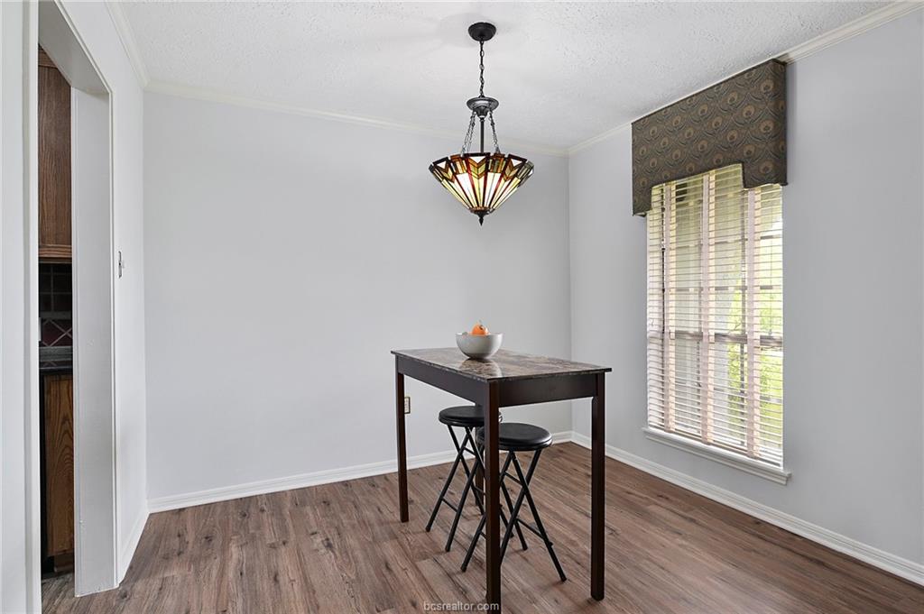 1031 Rose Circle College Station, TX 77840 - Photo 8 of 26 Dining space featuring dark wood-style flooring, crown molding, and a textured ceiling