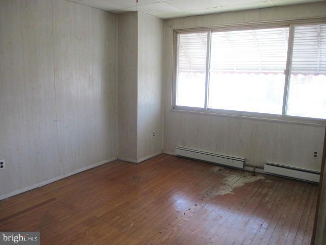 7044 Belclare Road Baltimore, MD 21222 - Photo 4 of 8 an empty room with wooden floor and windows