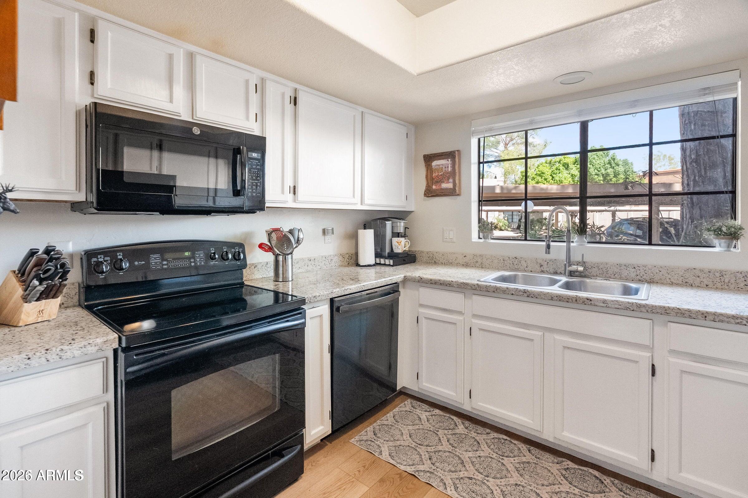 6885 East Cochise Road, Unit 132 Paradise Valley, AZ 85253 - Photo 2 of 10 a kitchen with stainless steel appliances granite countertop a sink dishwasher a stove and a microwave oven with cabinets