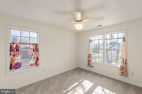 an empty room with windows and ceiling fan