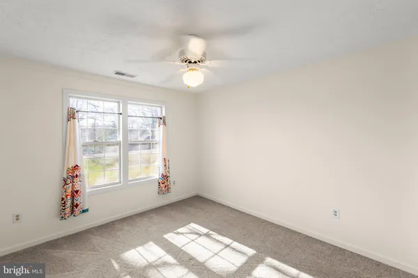 an empty room with closet and a ceiling fan