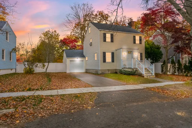 a view of a white house with a yard and plants