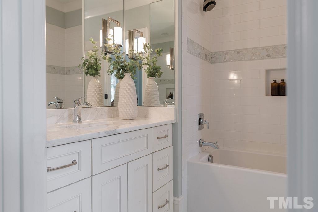 4427 Laurel Hills Road Raleigh, NC 27612 - Photo 70 of 89 a bathroom with a granite countertop sink a shower and a mirror