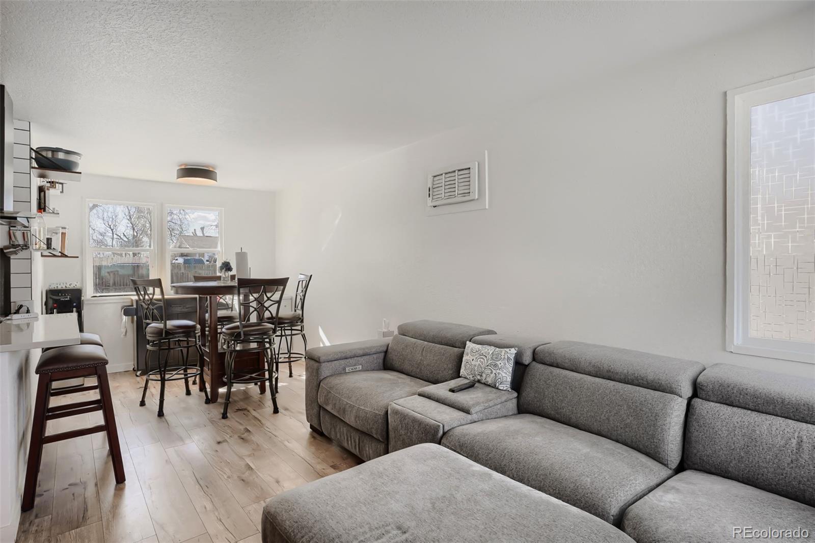 6461 Porter Way Commerce City, CO 80022 - Photo 4 of 23 a living room with furniture a dining table and chairs with kitchen view