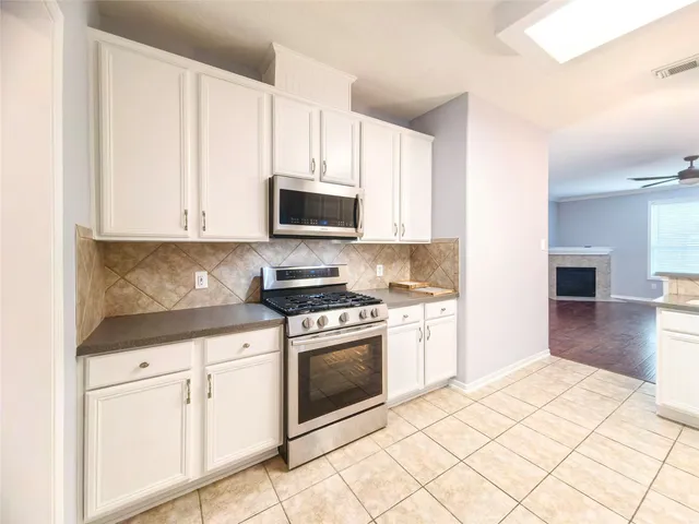 a kitchen with granite countertop white cabinets and appliances