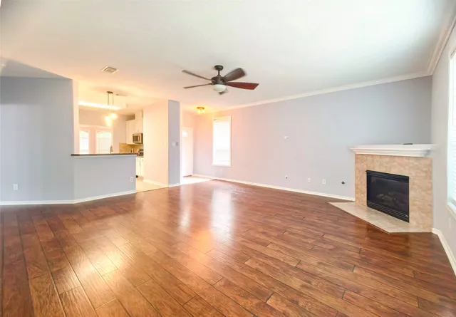 a view of an empty room with window and wooden floor