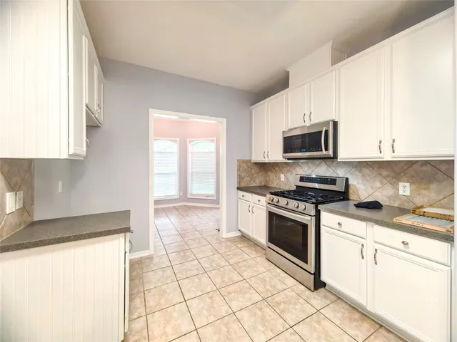 a kitchen with stainless steel appliances granite countertop a stove a sink and a microwave