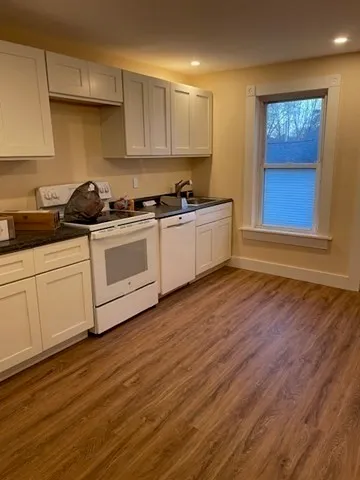 a kitchen with stainless steel appliances granite countertop a white cabinets a sink and dishwasher with wooden floor