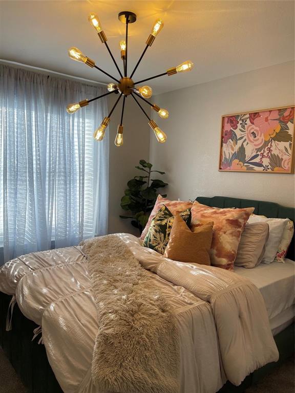 3063 Hells Gate Loop, Unit 23 Strawn, TX 76475 - Photo 12 of 36 a bedroom with a large bed and a chandelier