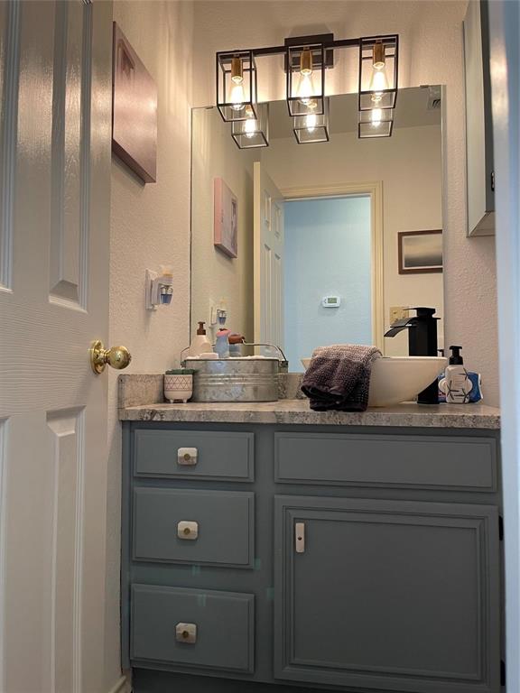 3063 Hells Gate Loop, Unit 23 Strawn, TX 76475 - Photo 14 of 36 a bathroom with a granite countertop sink a mirror and shower