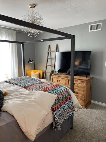 a bedroom with a bed and a flat tv screen on dresser