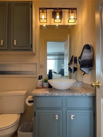 a bathroom with a granite countertop toilet sink and mirror