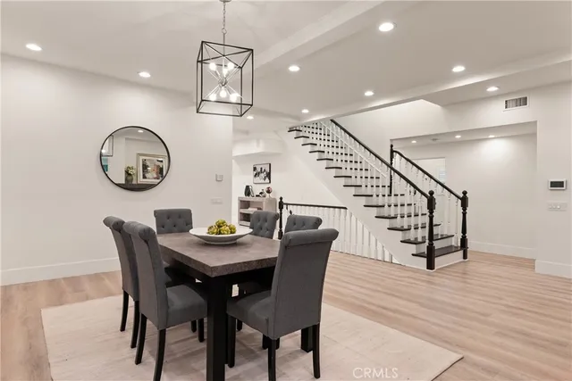 a dining room with wooden floor a chandelier a wooden table and chairs