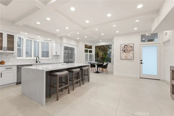 a large white kitchen with cabinets chairs and a sink