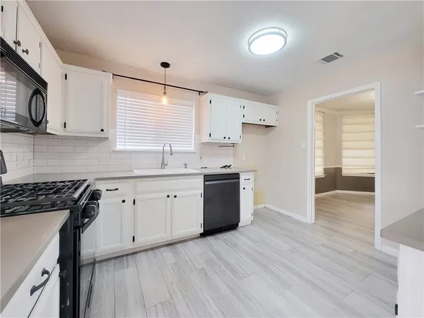 a kitchen with a sink cabinets stainless steel appliances and a window