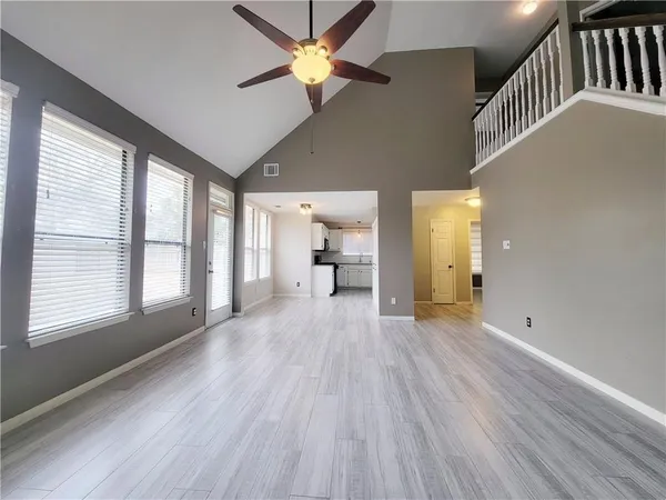 a view of empty room with wooden floor and fan