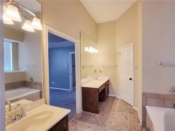 a spacious bathroom with a tub sink and mirror