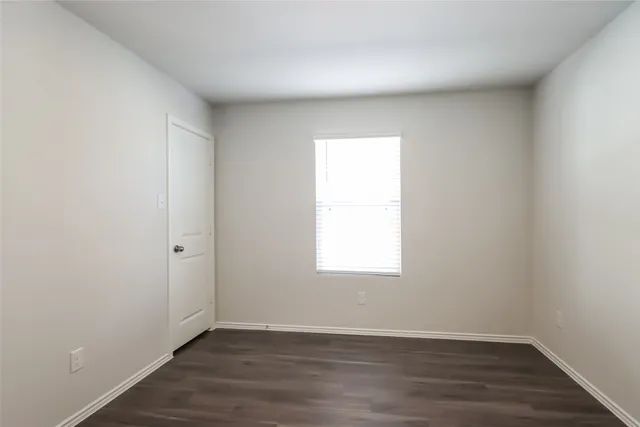 an empty room with wooden floor and window