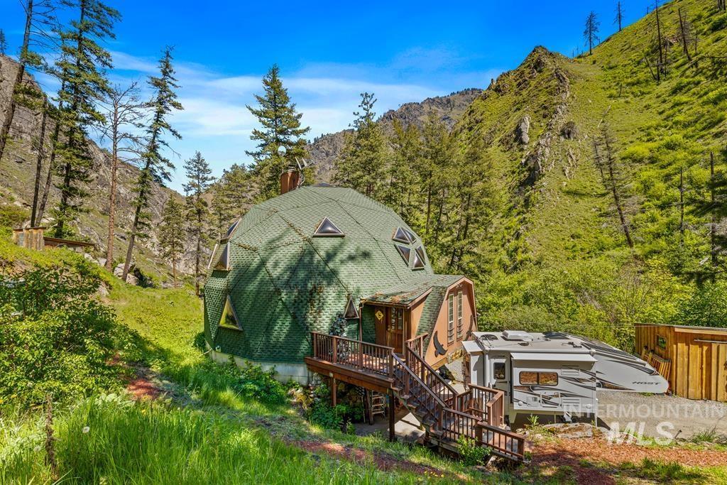 Rear view of house featuring a gambrel roof, a chimney, and a deck with mountain view