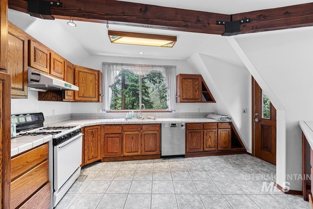 360 Lake Creek Riggins, ID 83549 - Photo 10 of 50 Kitchen featuring white gas range oven, tile counters, dishwasher, wood finish cabinetry, and lofted ceiling