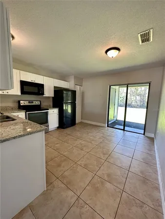 a view of an empty room with a window and a kitchen