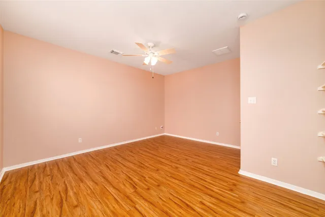 a view of empty room with wooden floor and fan