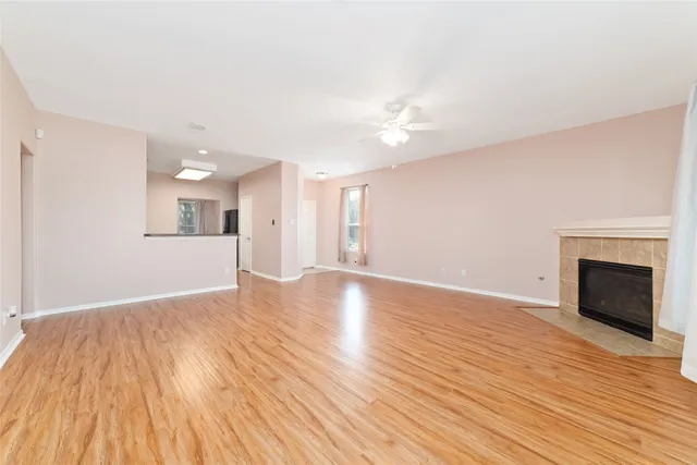 a view of an empty room with wooden floor and a fireplace