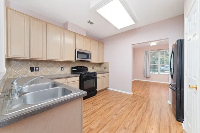 a kitchen with a sink wooden floor and stainless steel appliances