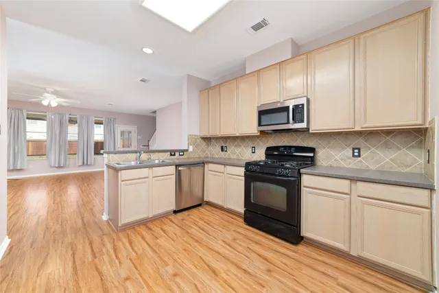 a kitchen with granite countertop wooden floors stainless steel appliances and white cabinets