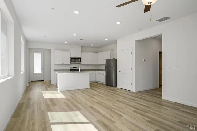 a kitchen with stainless steel appliances kitchen island wooden floors wooden cabinets and entryway